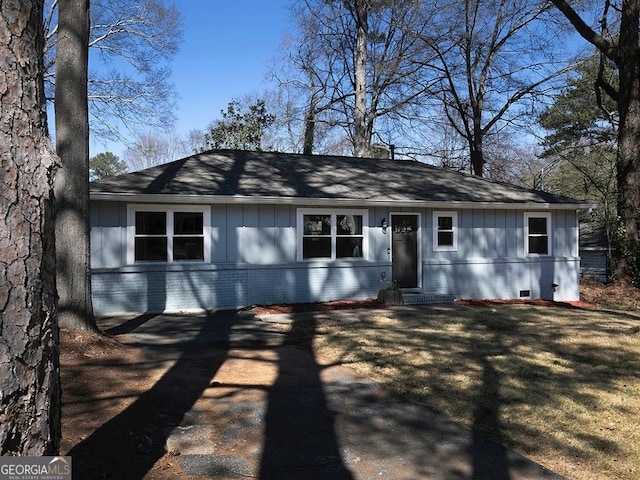 ranch-style home with board and batten siding, a front yard, crawl space, and brick siding