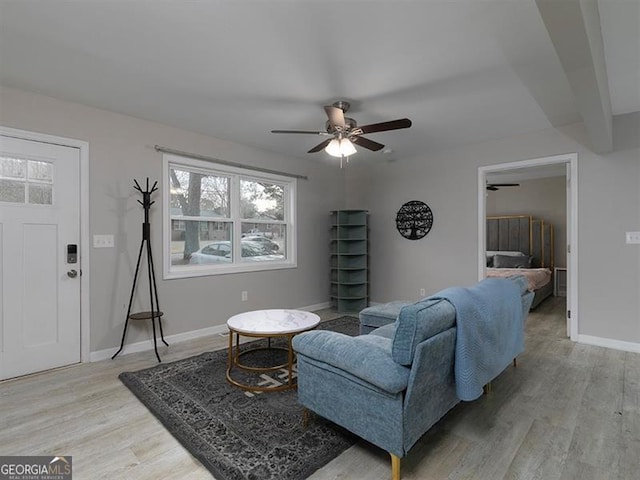 living area featuring light wood-type flooring, a ceiling fan, and baseboards