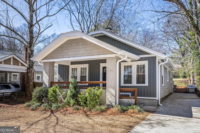 bungalow-style home with brick siding, a porch, and board and batten siding