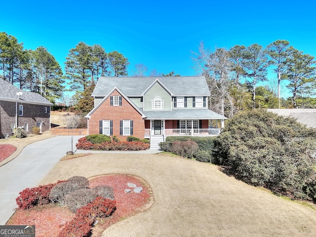 view of front of property with driveway, a porch, and brick siding