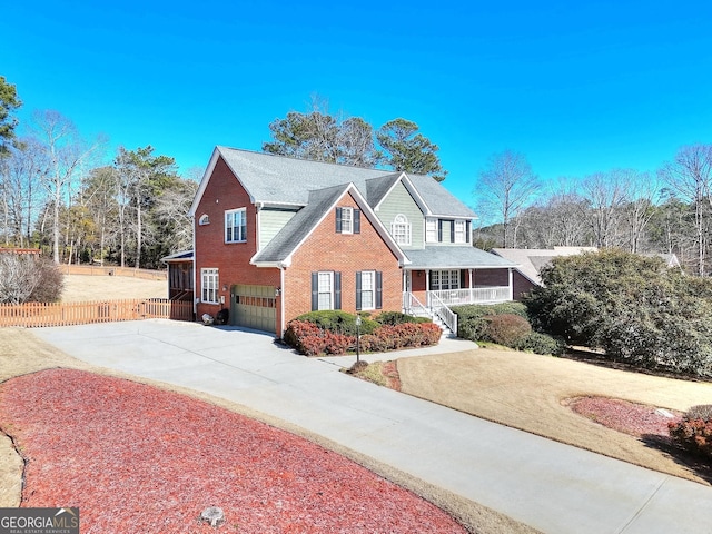 traditional-style home featuring a porch, brick siding, driveway, and fence