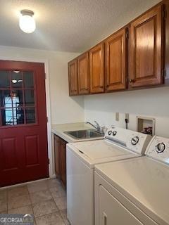 laundry room with cabinet space, washer and clothes dryer, a sink, and light tile patterned flooring