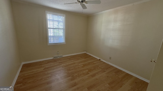 unfurnished room with ornamental molding, wood finished floors, visible vents, and a ceiling fan