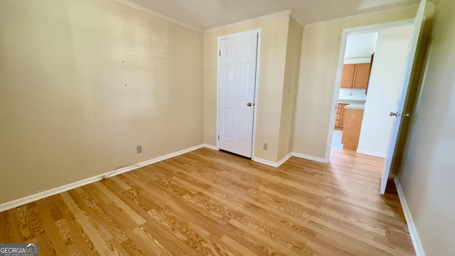 unfurnished bedroom featuring light wood-style flooring, baseboards, and ornamental molding