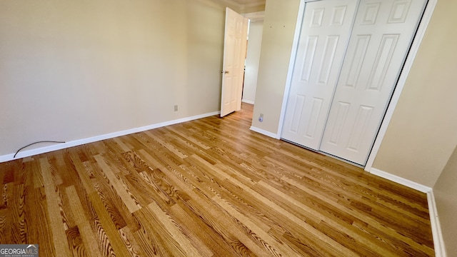 unfurnished bedroom featuring light wood-type flooring, baseboards, and a closet