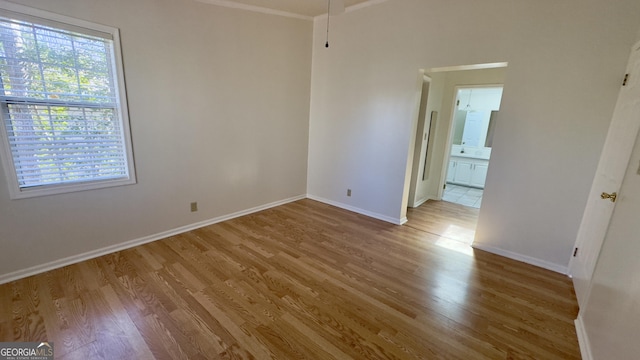 unfurnished bedroom featuring ornamental molding, wood finished floors, connected bathroom, and baseboards