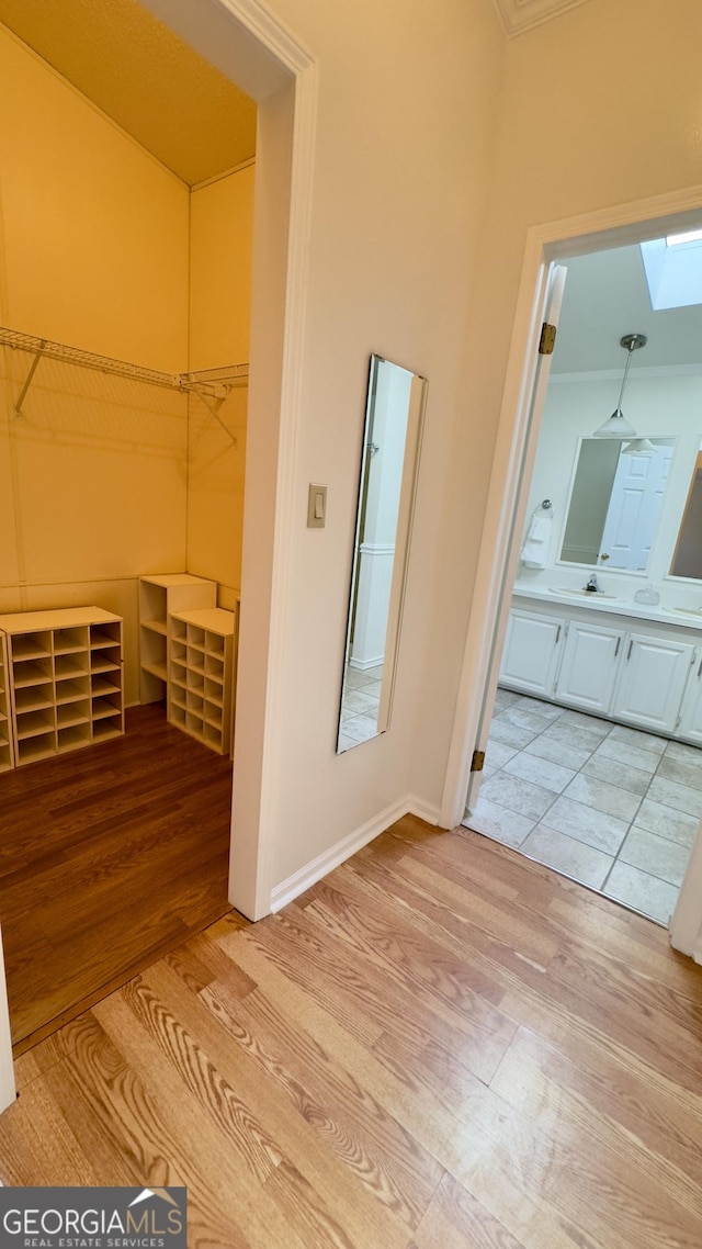 spacious closet featuring light wood-type flooring and a skylight