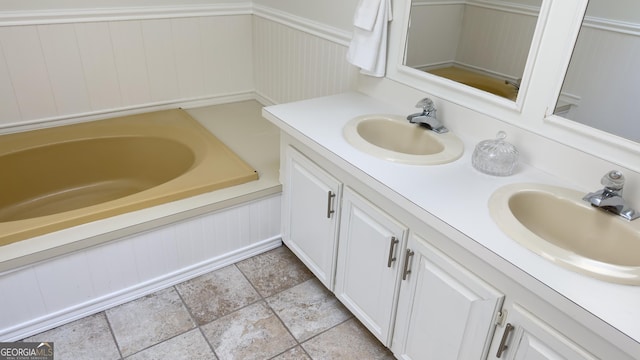 full bathroom featuring double vanity, stone finish floor, a sink, and a bath