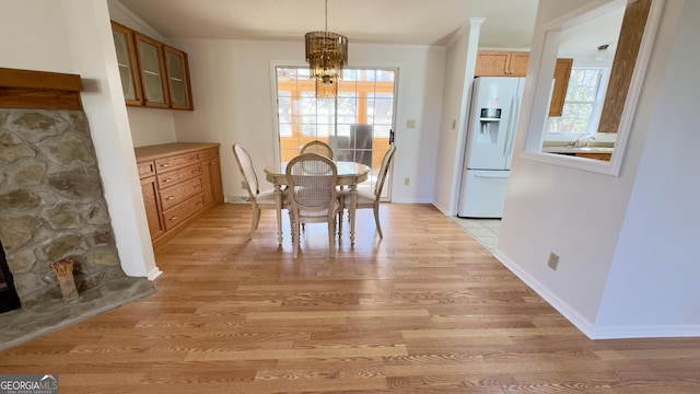 dining room featuring light wood-style floors, crown molding, baseboards, and an inviting chandelier