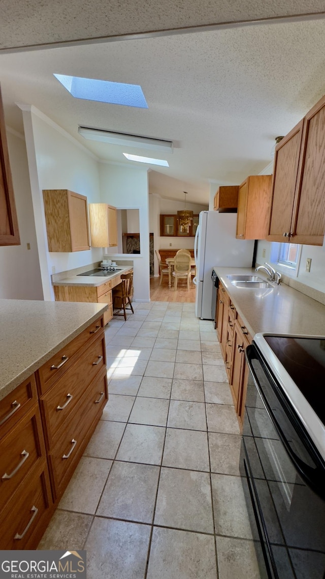 kitchen with a skylight, brown cabinets, light countertops, black electric range, and a sink