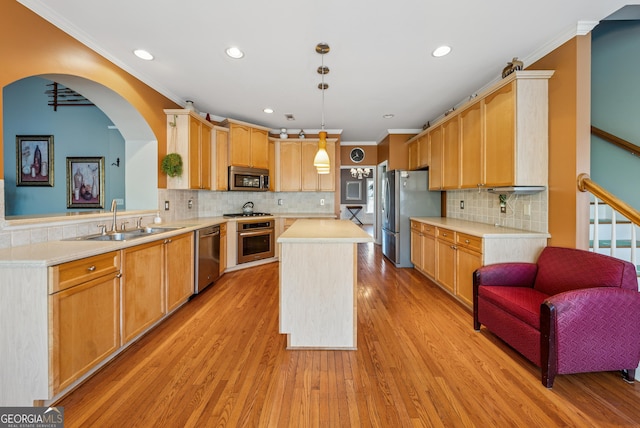 kitchen with a center island, light countertops, appliances with stainless steel finishes, ornamental molding, and a sink