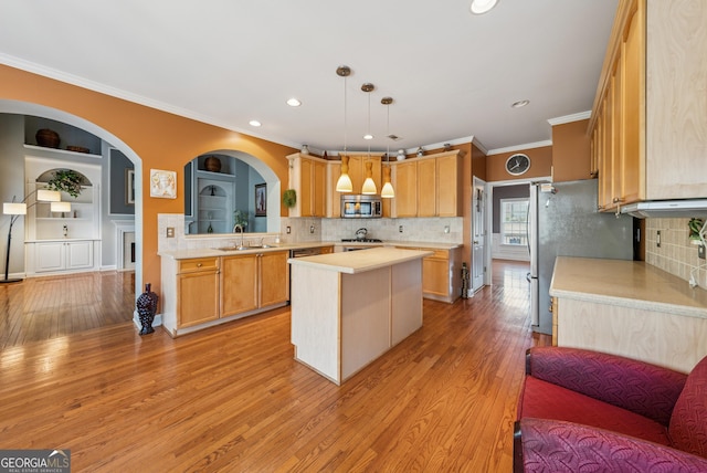 kitchen featuring a center island, light countertops, appliances with stainless steel finishes, a sink, and light wood-type flooring