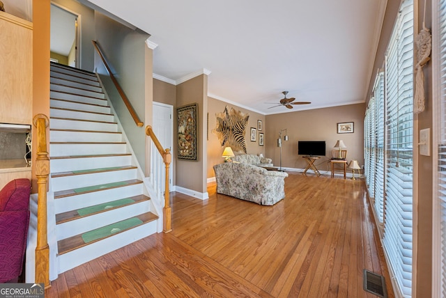 living room with stairway, wood-type flooring, visible vents, and crown molding