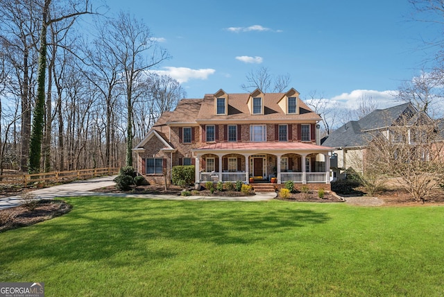 view of front facade featuring a porch, a front yard, and brick siding