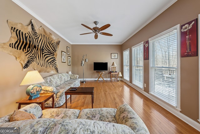 living area featuring ornamental molding, a ceiling fan, hardwood / wood-style floors, and baseboards