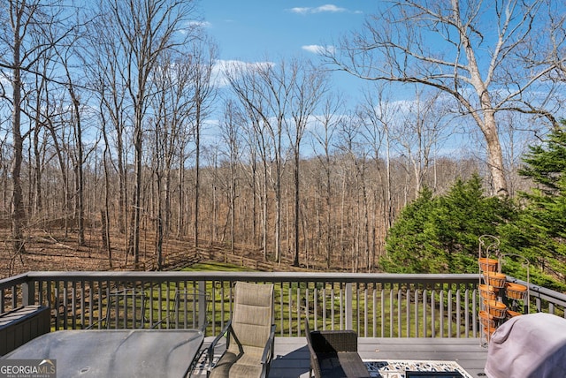 wooden deck featuring area for grilling and a wooded view