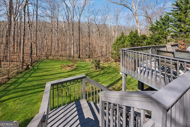 wooden terrace featuring a yard and a view of trees