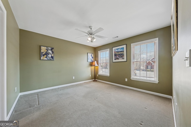 spare room featuring carpet, visible vents, ceiling fan, and baseboards