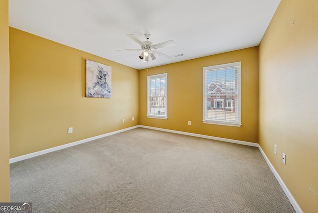 carpeted empty room featuring visible vents, baseboards, and a ceiling fan