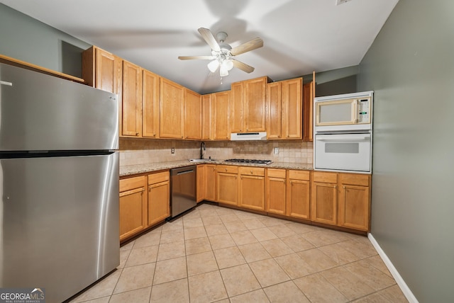 kitchen with light stone counters, light tile patterned floors, stainless steel appliances, backsplash, and under cabinet range hood