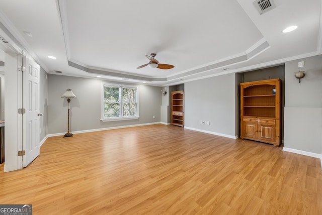 unfurnished living room featuring light wood-style flooring, visible vents, a raised ceiling, and ornamental molding