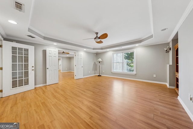 unfurnished living room with a tray ceiling, visible vents, ceiling fan, and light wood finished floors