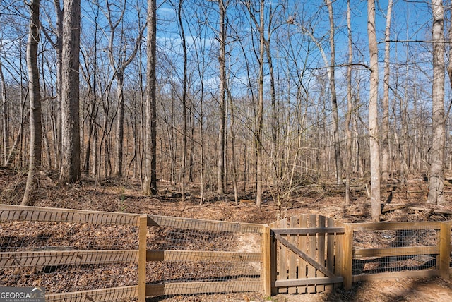 view of yard with a forest view, fence, and a gate