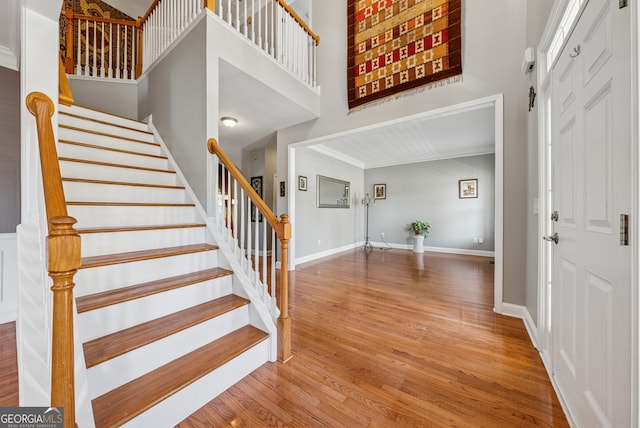 foyer featuring stairs, a high ceiling, baseboards, and wood finished floors