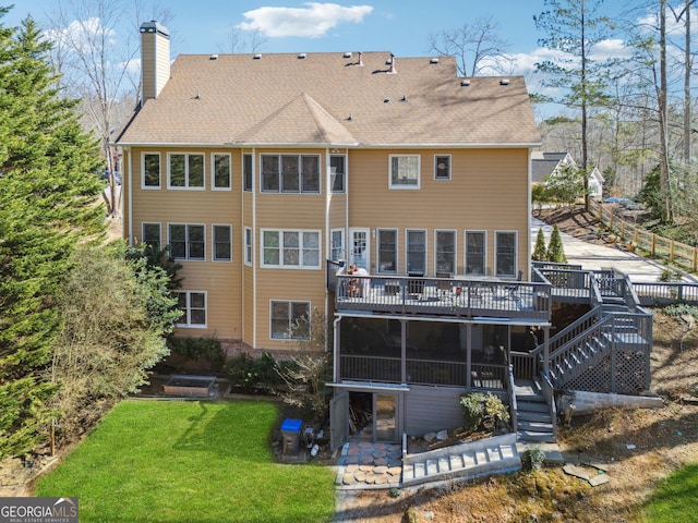 rear view of property with a chimney, a shingled roof, a lawn, stairway, and a deck