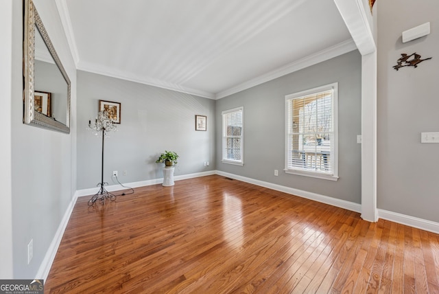 unfurnished room with ornamental molding, wood-type flooring, and baseboards