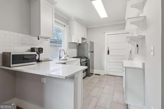 kitchen featuring a peninsula, stainless steel appliances, light countertops, white cabinetry, and a sink