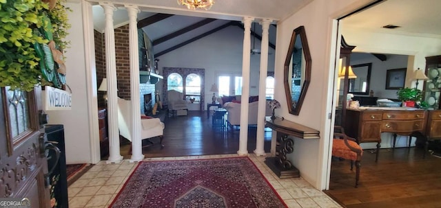 foyer featuring vaulted ceiling with beams, light wood-type flooring, a fireplace, and decorative columns