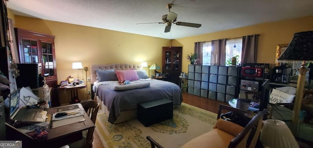 bedroom with ceiling fan, a textured ceiling, and wood finished floors