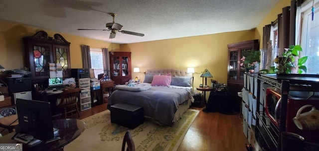 bedroom with a textured ceiling, wood finished floors, and a ceiling fan