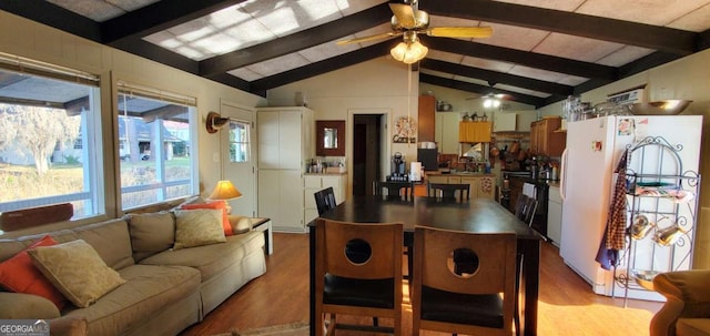 dining space featuring lofted ceiling with beams, wood finished floors, and a ceiling fan