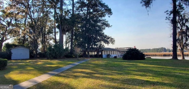 view of yard with a water view, a storage shed, and an outbuilding