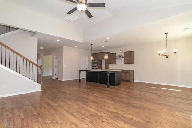 unfurnished living room with dark wood finished floors, recessed lighting, stairway, baseboards, and ceiling fan with notable chandelier