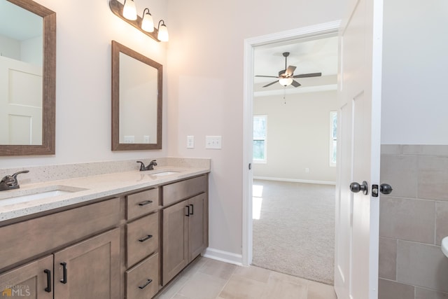 full bathroom with double vanity, ceiling fan, baseboards, and a sink