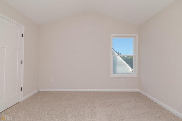 unfurnished room featuring carpet, vaulted ceiling, and baseboards