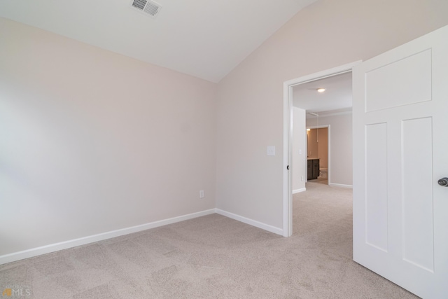 empty room with lofted ceiling, baseboards, visible vents, and light colored carpet