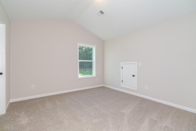 unfurnished room featuring baseboards, visible vents, vaulted ceiling, and carpet flooring