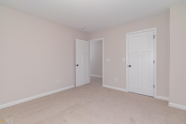 spare room with light carpet and baseboards