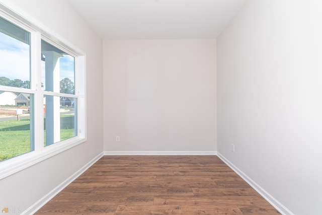 spare room with baseboards, dark wood-type flooring, and a healthy amount of sunlight