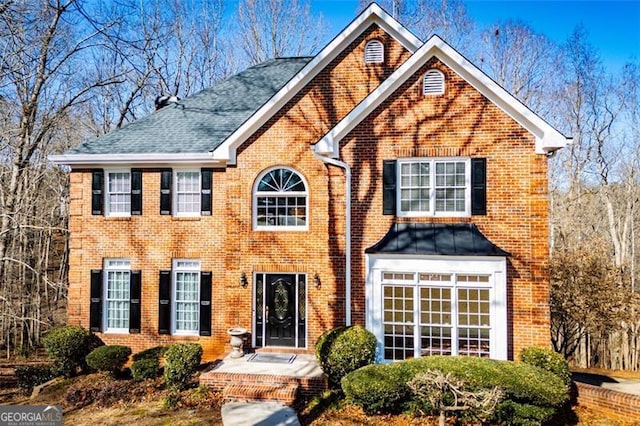 colonial home with a shingled roof and brick siding