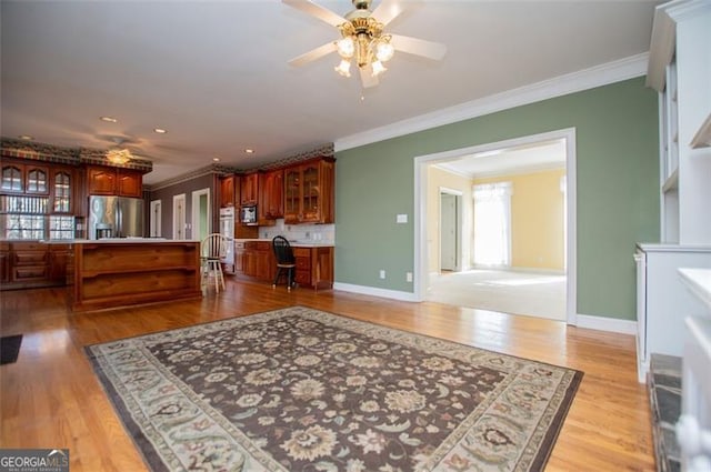 kitchen featuring light wood-style floors, baseboards, appliances with stainless steel finishes, and ornamental molding