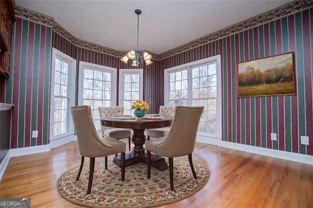 dining space featuring wallpapered walls, baseboards, and a notable chandelier