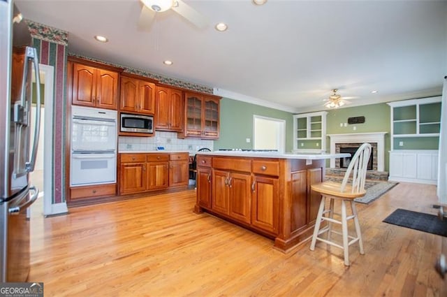 kitchen featuring light countertops, appliances with stainless steel finishes, a ceiling fan, open floor plan, and a kitchen island