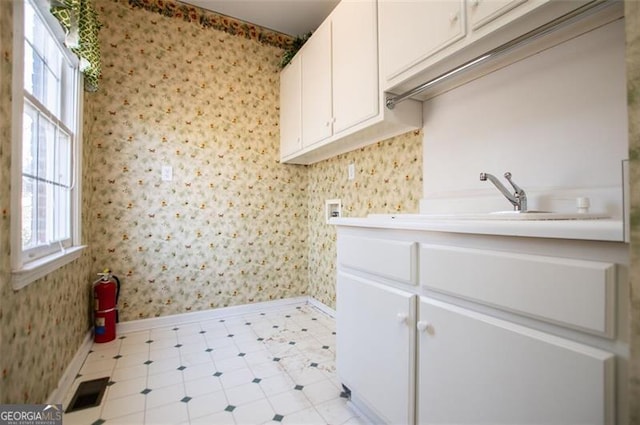 clothes washing area featuring baseboards, washer hookup, cabinet space, and wallpapered walls
