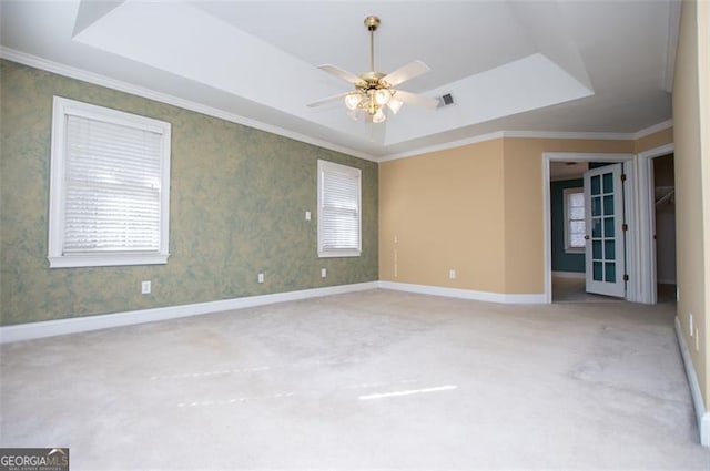 unfurnished room with baseboards, a tray ceiling, a ceiling fan, and ornamental molding