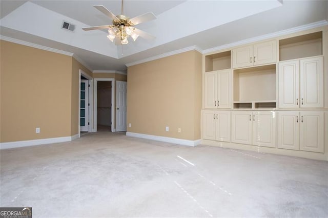 unfurnished bedroom featuring light carpet, visible vents, baseboards, a raised ceiling, and crown molding